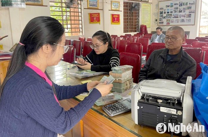 Cán bộ Hội đồng GPMB huyện Hưng Nguyên đếm tiền để bàn giao cho ông Nguyễn Văn Lộc. Ảnh: Tiến Đông