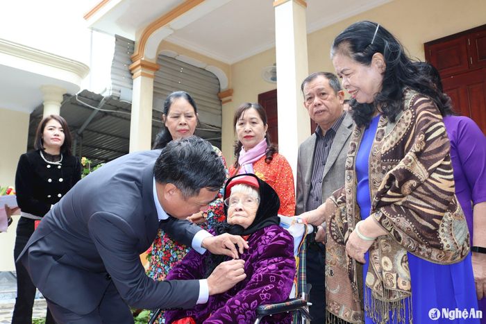 Thừa ủy quyền của Thường trực Tỉnh ủy, đồng chí Hoàng Văn Bộ - Bí thư Huyện ủy Quỳnh Lưu trân trọng gắn Huy hiệu 80 năm tuổi Đảng, trao chứng nhận và tặng hoa chúc mừng đảng viên Đậu Thị Phương. Ảnh: Việt Hùng