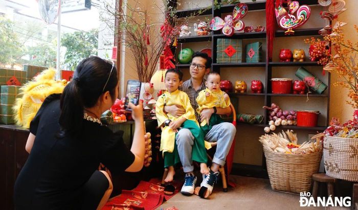 Các quán cà phê tận dụng cả không gian ngoài trời lẫn trong nhà để trang trí Tết. Với thời tiết lạnh, thỉnh thoảng có mưa, việc chụp hình Tết tại quán cà phê được khá nhiều bạn trẻ, gia đình có con nhỏ ưa chuộng. TRONG ẢNH: Các em bé được ba mẹ diện áo dài để chụp hình đón Tết tại quán cà phê Reply 1988 (quận Hải Châu).