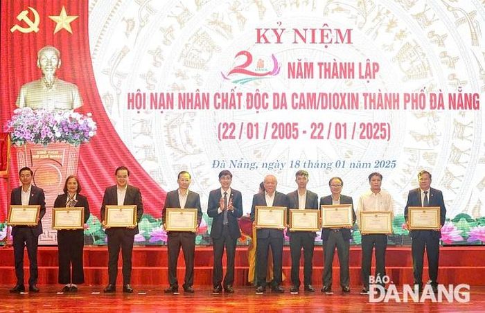 Trưởng Ban Dân vận Thành ủy Trần Thắng Lợi (thứ 5, bên trái qua) trao bằng khen của UBND thành phố cho các tập thể có thành tích xuất sắc trong thực hiện phong trào thi đua “Chung tay xoa dịu nỗi đau da cam” giai đoạn 2005-2025. Ảnh: L.P