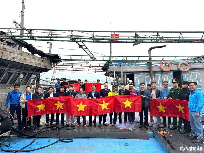 Trao tượng trưng cờ Tổ quốc cho ngư dân về neo đậu tại Cảng cá Quỳnh Phương, TX. Hoàng Mai. Ảnh: Nguyễn Hải