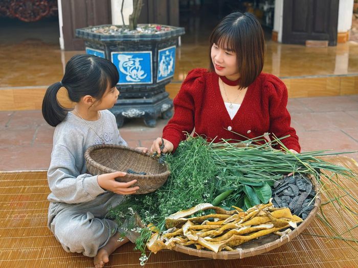 Chị Dung cùng con chuẩn bị các loại lá cây để đun nước.