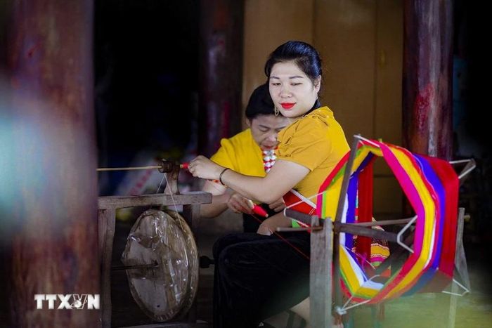 Phụ nữ dân tộc Thái kéo sợi để dệt khăn Piêu. (Ảnh: Xuân Tư/TTXVN)