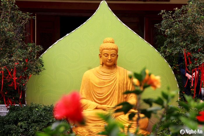 Bức tượng Phật được đặt trước chính điện ngôi chùa, nổi bật giữa vườn hoa khoe sắc. Ảnh: P.V