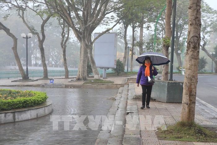 Người dân phải dùng ô vì trời xuất hiện mưa phùn, mưa nhỏ ở khu vực đường Thanh Niên và Hồ Tây. Ảnh: Nguyễn Hoa/TTXVN phát