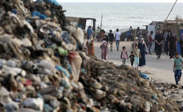 Mọi người đi ngang qua những đống rác ở Deir al Balah, Gaza vào ngày 26 tháng 5. (Ảnh: GI/Getty)