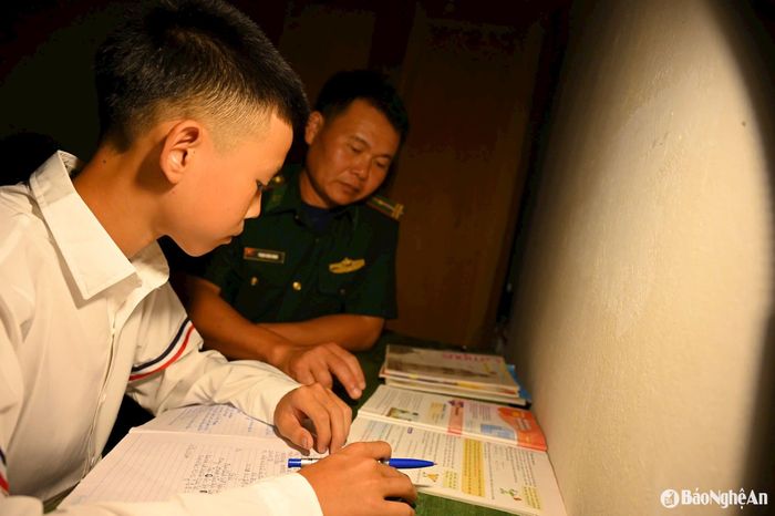 Cán bộ Đồn Biên phòng Na Ngoi (Kỳ Sơn) hướng dẫn con nuôi của đồn học bài. Ảnh: Hải Thượng