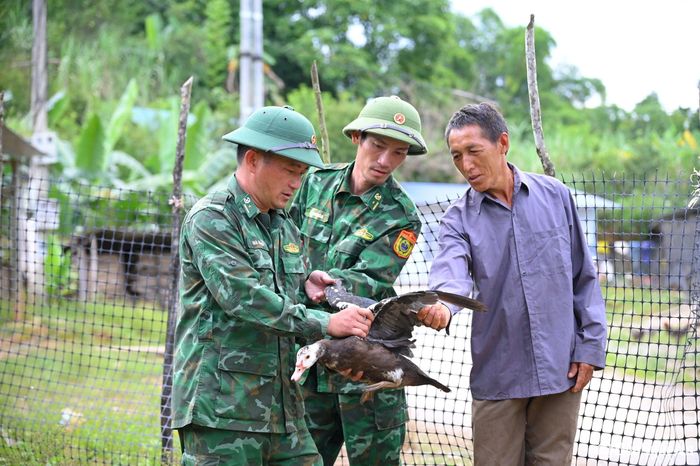Cán bộ Đồn Biên phòng Na Ngoi (Kỳ Sơn) hướng dẫn người dân chăm sóc vật nuôi. Ảnh: Khánh Ly
