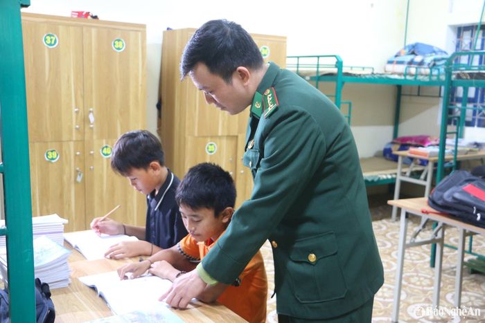 Cán bộ Đồn Biên phòng Tam Quang (Tương Dương) hướng dẫn học sinh ở ký túc xá vùng biên học bài. Ảnh: Khánh Ly