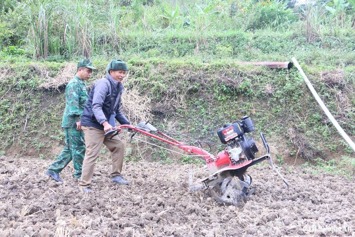 Cán bộ đồn biên phòng Mường Ải (Kỳ Sơn) hướngdẫnngười dân sử dụng máy cày mi ni. Ảnh: Khánh Ly