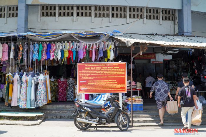  Nhiều tiểu thương vẫn đang buôn bán bên ngoài khu vực chợ Đầm tròn, dù chính quyền thành phố đặt biển cảnh báo công trình nguy hiểm. Ảnh: HIẾU GIANG 