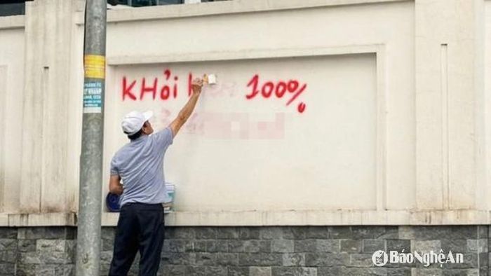 Người dân phải tự mua sơn về xóa dòng chữ quảng cáo. Ảnh: T.Đ