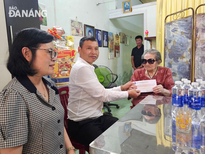 Phó Chủ tịch Thường trực UBND thành phố Hồ Kỳ Minh (thứ 2, bên trái qua) tặng quà đến bà Phạm Thị Thiên Hương. Ảnh: L.P