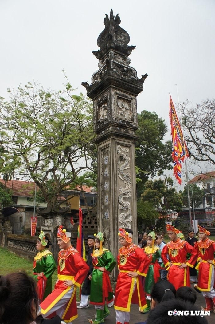 Đội cờ người diễu hành qua cây cột đồng trụ cổ kính