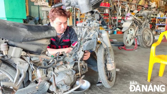 Với đặc thù công việc cùng tinh thần sống “tàn nhưng không phế”, anh Quyền luôn nỗ lực học hỏi mỗi ngày, cập nhật kiến thức mới để nâng cao tay nghề trong công việc sửa chữa xe máy. Ảnh: THU HƯƠNG