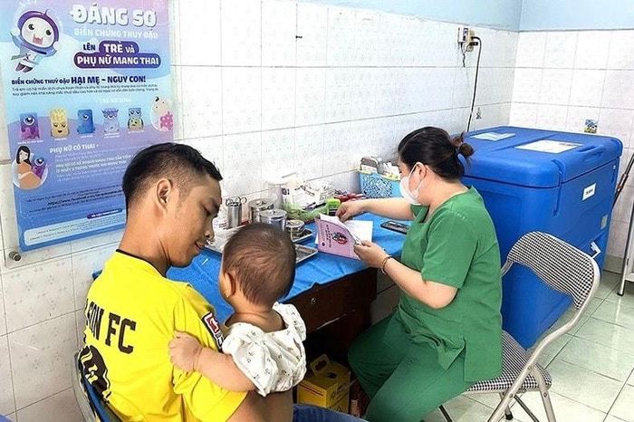 Người dân đưa trẻ đến Trạm y tế phường 8, quận Gò Vấp để tiêm vắc xin trong chương trình tiêm chủng mở rộng
