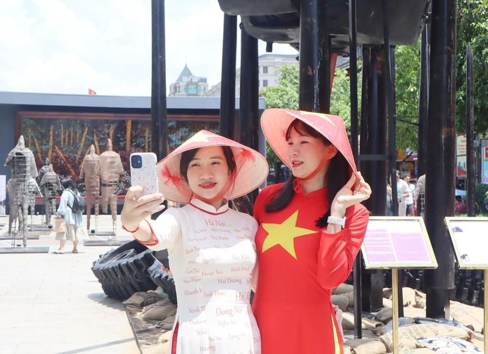 Người dân diện áo dài truyền thống, cờ đỏ sao vàng ghi lại những khoảnh khắc đẹp trong dịp lễ kỷ niệm. Ảnh: Thu Hương - TTXVN