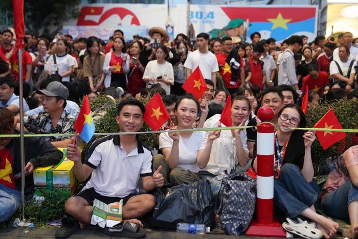  Nguyễn Thị Thủy (áo trắng, sống tại TP Thủ Đức) chờ xem các khối diễu binh và bắn đại bác từ 14h ngày 29/4 tại Bến Bạch Đằng (quận 1). "Tôi không ngại nắng hay chờ suốt đêm vì tôi yêu Việt Nam, các chiến sĩ đã chuẩn bị rất lâu cho Lễ kỷ niệm 50 lần này. Lần đầu xem diễu binh và bắn đại bác, tôi rất háo hức, cùng với đó là cảm giác hạnh phúc, tự hào khi thấy đất nước phát triển, người dân đoàn kết", cô bày tỏ. Ảnh: Linh Huỳnh. 