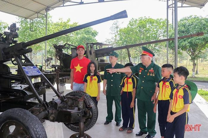  Các hiện vật được trưng bày tại khu di tích luôn thu hút sự quan tâm của giới trẻ. Trong ảnh: Các cựu chiến binh Tiểu đoàn 8 pháo cao xạ kể với các em nhỏ về những thành tích của chiếc pháo tiểu đội vận hành trong kháng chiến chống Mỹ. 