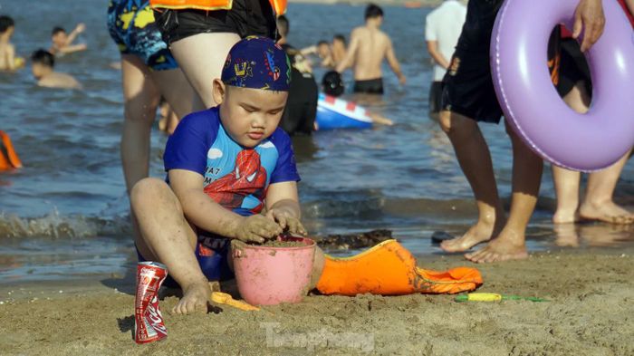 Các em nhỏ nô đùa bên bờ cát, ôm phao tắm biển.