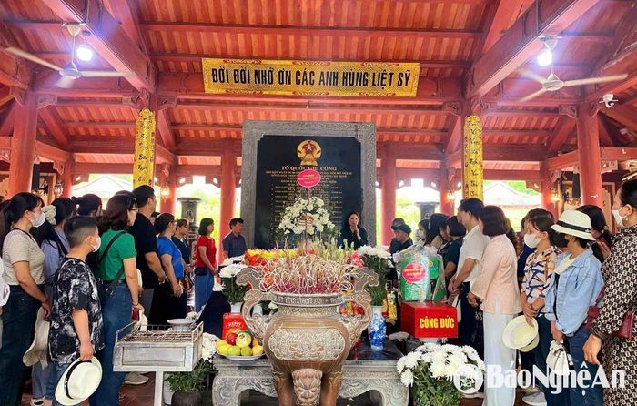 Bên ngôi mộ chung của 13 liệt sĩ thanh niên xung phong, du khách lắng lòng nghe cán bộ, nhân viên Khu Di tích kể về "tọa độ lửa" Truông Bồn và giây phút hy sinh đầy xúc động của các liệt sĩ. Ảnh: Huy Thư