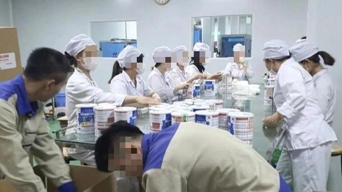 Công nhân đóng hộp thành phẩm tại cơ sở sản xuất sữa bột giả bị Công an thành phố Hà Nội triệt phá