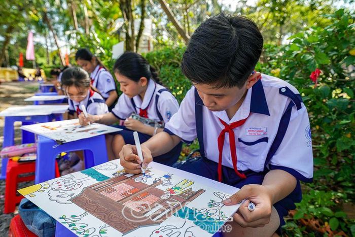 Em Trần Tấn Nam, Lớp 5A, Trường Tiểu học Hùng Vương, say sưa bên tác phẩm “Hoa thơm dâng Bác”.