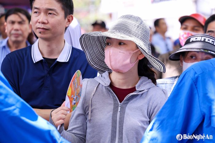 Một số người tranh thủ dùng quạt tay, quạt tiện lợi để giảm bớt cái oi ả. Có người ngồi lặng lẽ nhìn vào cổng trường, ánh mắt như dõi theo từng giờ thi của con. Ảnh: Đức Anh