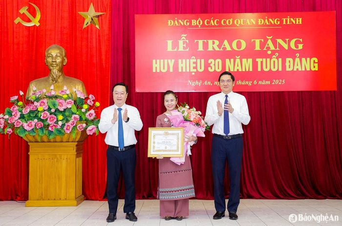 Các đồng chí: Nguyễn Đức Trung - Bí thư Tỉnh ủy; Hoàng Nghĩa Hiếu - Phó Bí thư Thường trực Tỉnh ủy, Chủ tịch HĐND tỉnh, Bí thư Đảng ủy Các cơ quan Đảng tỉnh đã trao quyết định, gắn Huy hiệu 30 năm tuổi Đảng, tặng hoa chúc mừng đồng chí Võ Thị Minh Sinh. Ảnh: Phạm Bằng