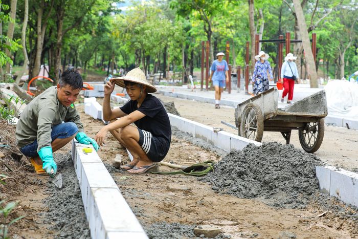 Đơn vị thi công đang tiến hành thi công bó vỉa hè trong Công viên Cầu Giấy. Ảnh: TTXVN