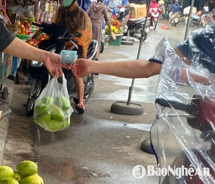 Một tiểu thương bán hoa quả tại chợ Vinh nhận tiền mặt của khách. Ảnh: Hải An