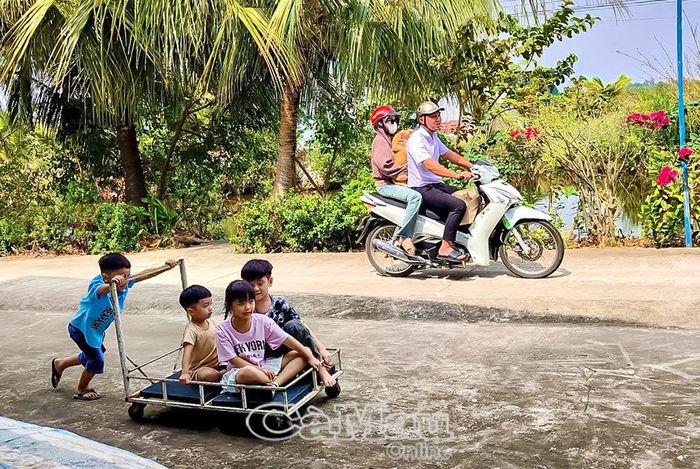 Trẻ nhỏ nô đùa trước sân nhà, làm rộn vui không khí miền quê yên bình.