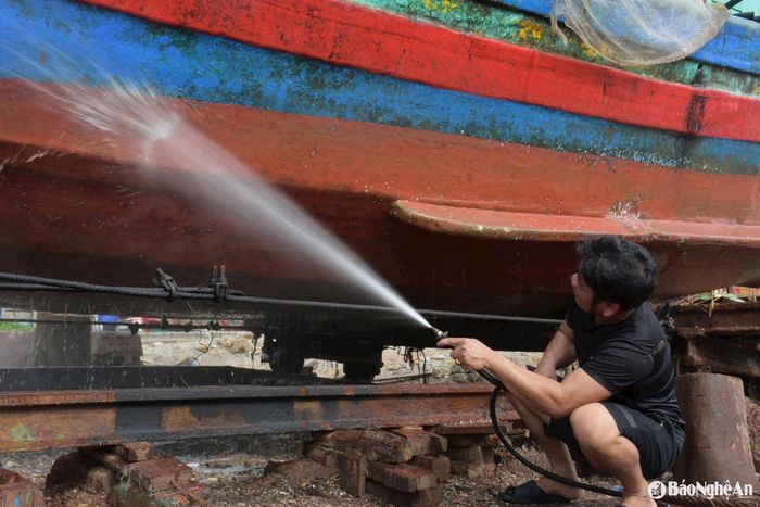 Mỗi vết rạn, mỗi lớp hàu bám trên thân tàu đều được công nhân xịt rửa sạch sẽ. Không chỉ cần sức khỏe, công đoạn này còn đòi hỏi sự cẩn trọng để tránh làm tổn hại lớp vỏ gỗ hoặc sắt vốn đã mỏi mòn vì nước biển. Ảnh: T.P