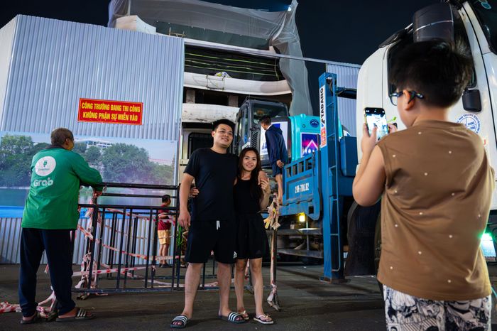  Phía bên ngoài quảng trường Đông Kinh Nghĩa Thục, việc phá dỡ tòa nhà "Hàm cá mập" thu hút sự chú ý của người dân và du khách check-in, chụp hình kỷ niệm. "Tôi biết tới tòa nhà 'Hàm cá mập' từ lâu và cũng có nhiều kỷ niệm tại đây, nay tình cờ đi chơi cùng gia đình ngang qua thấy công trình đang tháo dỡ nên dừng lại chụp ảnh kỷ niệm cùng gia đình. Tôi cũng rất mong chờ diện mạo mới của quảng trường Đông Kinh - Nghĩa Thục rộng rãi hơn để đáp ứng nhu cầu vui chơi và giải trí của người dân", chị Nguyễn Thị Oanh (34 tuổi, quận Hai Bà Trưng) nói.