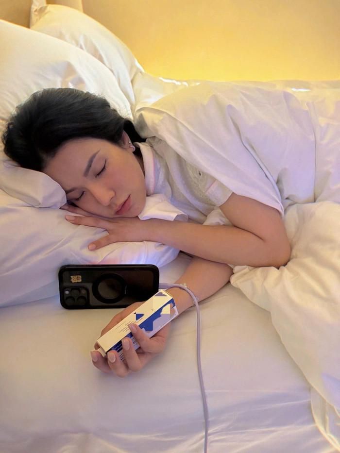 Diệp Lâm Anh mệt mỏi nằm thiếp trên giường, trên tay vẫn cầm lọ thuốc. Ảnh: FBNV