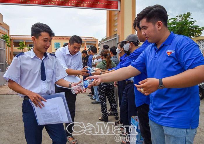 Lực lượng tình nguyện viên điểm thi Trường THPT Cái Nước phát nước và thức ăn cho các thí sinh. Ảnh: VĂN ĐUM