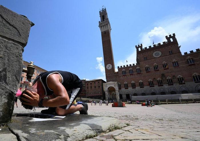 Một người đàn ông làm mát tại đài phun nước ở Siena, Italy. Ảnh: THX/TTXVN