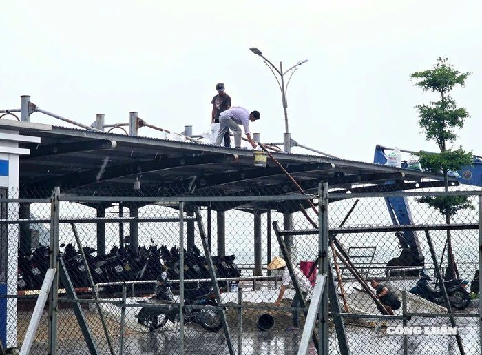 Nhiều cơ quan, doanh nghiệp chủ động dùng bao cát đè mái tôn, chằng chống nhà cửa trước khi báo đổ bộ đến.