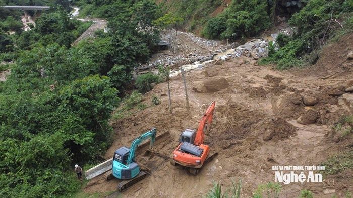 Các đơn vị quản lý giao thông huy động máy móc san gạt, khắc phục tình trạng sạt lở trên Quốc lộ 16 đoạn qua xã Nhôn Mai. Ảnh: PV