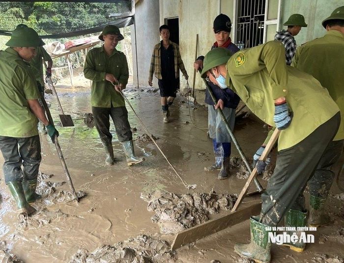 Cán bộ Kiểm lâm dọn bùn đất giúp một hộ dân tại xã Tương Dương sau lũ. Ảnh: PV
