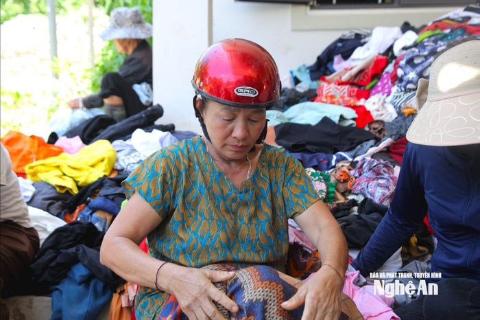 Bà Lê Thị Hà hỗ trợ sắp xếp, phân phối quần áo cứu trợ. Ảnh: Ngân Hạnh