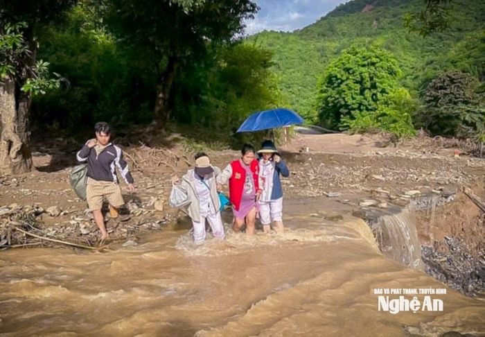 Sản phụ được cán bộ Trạm Y tế Mường Típ dìu qua suối và các điểm sạt lở. Ảnh: Ý Huệ