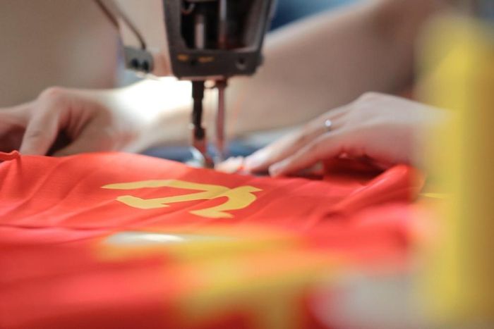 Những máy may cờ Tổ quốc, cờ Đảng hoạt động hết công suất. Ảnh: Lê Đông - TTXVN