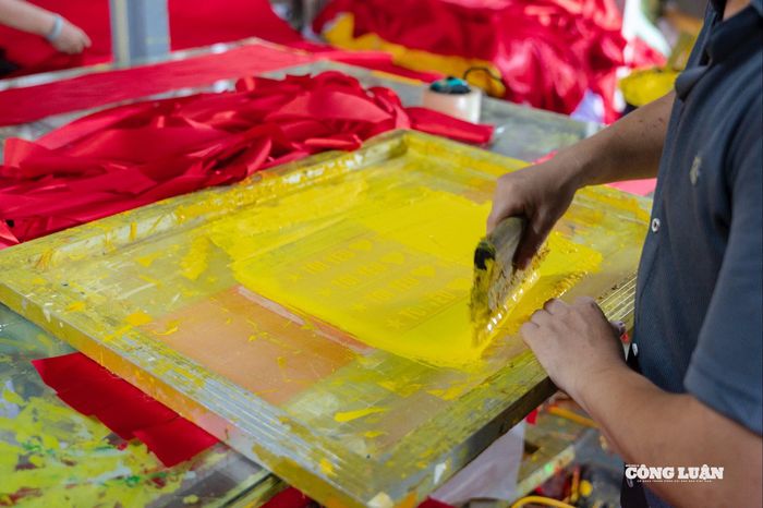 Sau khi chuẩn bị xong vải, công đoạn tiếp theo là cắt theo kích thước quy định, sau đó in hoặc thêu ngôi sao vàng ở chính giữa lá cờ. Nếu sử dụng kỹ thuật in, cờ sẽ được mang đi phơi hoặc sấy khô để mực bám đều và bền màu.