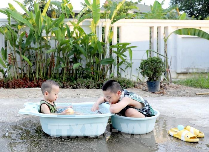 Cho trẻ con tắm tại bể bơi, thau, chậu chứa nước.. là một trong những cách giải nhiệt mùa hè cho con của các bậc phụ huynh. Ảnh chụp tại xã Tam Dương. Ảnh: Hoàng Hùng -TTXVN
