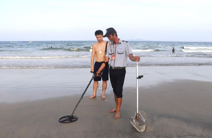 Lực lượng Đội quản lý trật tự du lịch biển, Ban quản lý bán đảo Sơn Trà và các bãi biển du lịch Đà Nẵng dùng máy dò tìm đồ vật cho du khách. Ảnh: Nguyễn Tú.