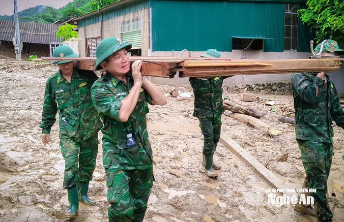 Cán bộ Đồn Biên phòng Mường Ải hỗ trợ người dân dọn dẹp sau lũ. Ảnh: Đình Tuyên