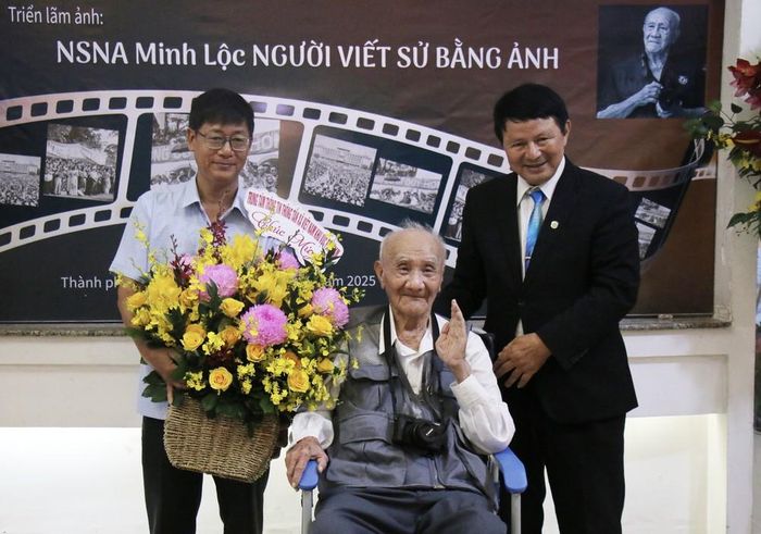 Ông Trần Tràng Dương, Phó Giám đốc Trung tâm Thông tin TTXVN khu vực phía Nam (bên trái) tặng hoa chúc mừng Nghệ sỹ nhiếp ảnh Minh Lộc. Ảnh: Thu Hương - TTXVN