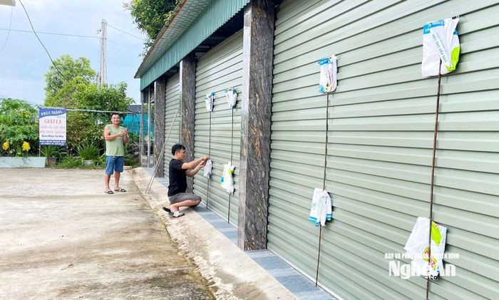 Người dân xã Lam Thành nẹp cửa cuốn để hạn chế tác hại của gió bão. Ảnh: Công Kiên