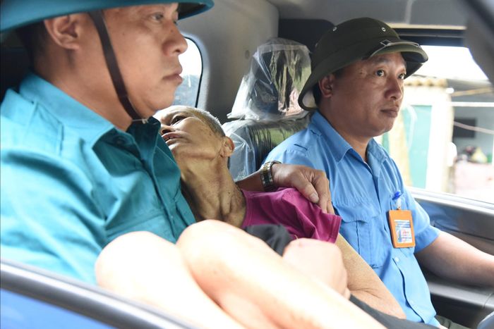 Lực lượng dân quân tự vệ, trật tự đô thị giúp di dời người già yếu của xóm Hòa Lam đến nơi an toàn tránh bão. Trong ảnh: Cụ bà Hoàng Thị Sanh - vợ thương binh (chồng đã mất hơn 1 năm), bị bệnh nặng không thể di chuyển, được lực lượng chức năng đón đến trạm y tế tránh bão. Ảnh: Hoài Thu